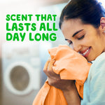 Woman smelling freshly washed orange fabric in a laundry room with copy reading scent that lasts all day long