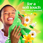 Woman smiling and pressing a green towel to her face against a bright green floral background with 'for a soft touch' copy