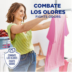 Smiling woman holding up a pink shirt in a laundry room with 'fights odors' text overlay