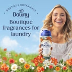 Smiling woman holding a Downy Citrea scent booster bottle with floral meadow graphics and tagline 'Boutique fragrances for laundry'.