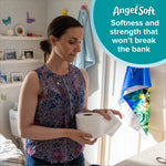 Woman in a bathroom holding and inspecting a toilet paper roll with an AngelSoft callout badge