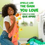 Woman hugging freshly laundered clothing with floral scent graphics and text about Gain fragrance