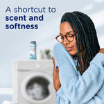 Woman hugging a sweater in front of a blurred washer with text 'A shortcut to scent and softness' promoting the product benefit