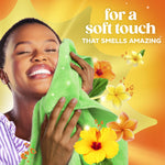 Woman joyfully pressing a green towel to her cheek with floral accents and text promoting a soft, amazing scent