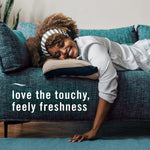 Lifestyle photo of a smiling woman reclining on a teal sofa with overlay text about touchy, feely freshness
