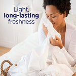 Woman inhaling a white sheet from a laundry basket with overlaid text reading "Light, long-lasting freshness"