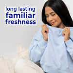 Woman smelling a light-blue sweatshirt with copy reading long lasting familiar freshness on a neutral background.