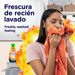 Woman smelling an orange towel with a small Downy bottle and floral halo in the background promoting freshly washed feeling