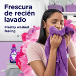 Woman smelling a purple towel with a Downy Intense Floral bottle visible and copy about freshly washed feeling