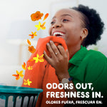 Woman happily smelling a bright orange towel with floating yellow flowers graphic and text ‘Odors out, freshness in’