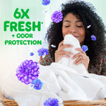 Woman smelling a white towel with floating purple flowers and text reading 6X FRESH + ODOR PROTECTION