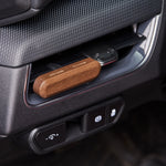 Wood-tone car vent diffuser clipped into a vehicle vent slot, showing product in situ near dashboard controls