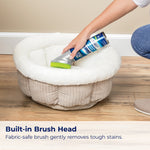 Woolite carpet & upholstery cleaner shown cleaning a plush pet bed with built-in brush head