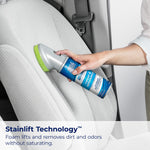 Person cleaning a light car seat with Woolite carpet & upholstery cleaner and built-in brush head