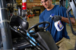 Worker cleaning a forklift interior and spraying with a GUNK multi-surface degreaser bottle