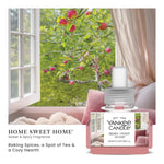Yankee Candle Home Sweet Home ScentPlug refill bottle placed in a cozy window scene with apples on a tree visible outside.