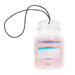 Clear jar-shaped Yankee Candle Pink Sands hanging car air freshener with black string and pink label