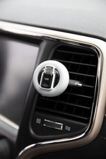 Yankee Candle vent clip attached to a vehicle air vent in a car interior, showing the clip and surrounding dashboard trim