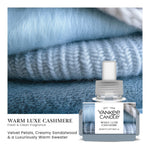 Yankee Candle Warm Luxe Cashmere refill bottle overlaid on a close-up image of soft blue knit fabrics