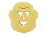 Top-down view of a yellow face-shaped sponge with smiling mouth and eye cutouts against white background