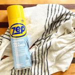 Zep Foaming Wall Cleaner can placed on a striped kitchen towel on a wooden surface, styled flat lay.