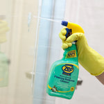 Hand in yellow glove spraying Zep Home Pro foaming bathroom cleaner onto a glass shower door