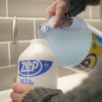 Close-up of hands pouring blue Zep liquid from a gallon jug into a smaller Zep E-Z Fill sprayer bottle