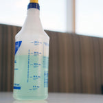 Close-up side view of Zep spray bottle showing volume measurement markings and pale liquid inside