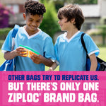 Two children in light blue jerseys smiling while one holds a clear Ziploc snack bag with a green zipper