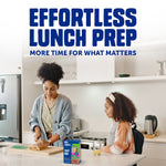 Lifestyle scene of a woman preparing a sandwich at a kitchen island with a child nearby and a Ziploc Lunch DUO box on the counter