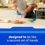 Lifestyle image of a person using a large Ziploc freezer bag on a kitchen counter with food and child partially visible, captioned 'designed to be like a second set of hands'