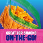 Close-up of a clear Ziploc bag with green textured zipper partially open showing square orange snack pieces